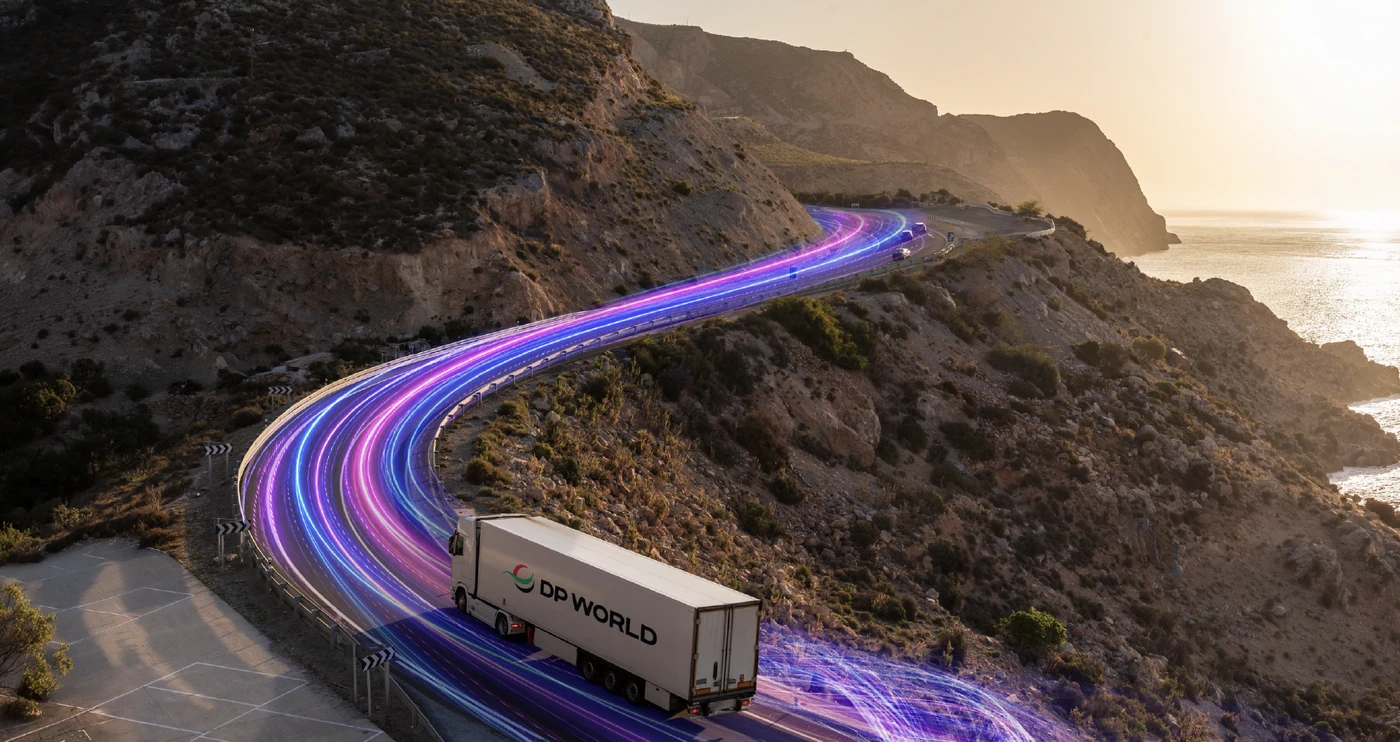 DP World promotional visual of a branded truck on a coastal mountain road with illuminated route trails