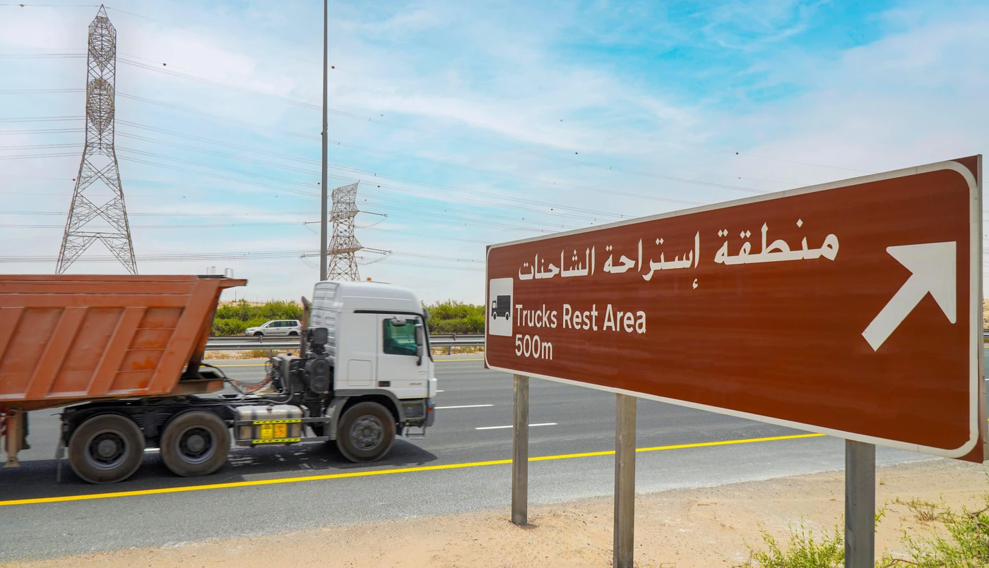 A truck beside a brown road sign directing drivers to a truck rest area 500 metres ahead
